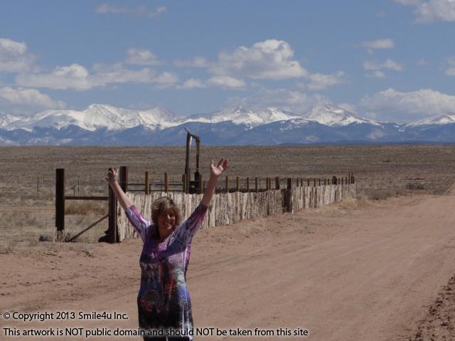 Char the Explorer standing on the road that runs along this land for sale in Costilla County, Colorado. There are gorgeous views of the Sangre de Cristo Mountains!